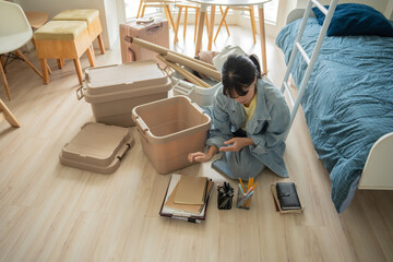 Student asian woman organize room unpack in dorm room college student moving to new  university dormitory or preparing to move out.