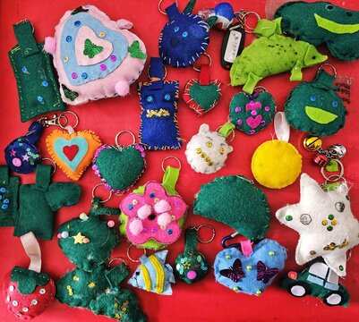Creativity of handicrafts made from fabric scraps into multicolored and shaped keychain dolls with isolated red backgrounds. Recycling concept.