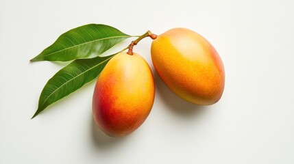 Two ripe mangoes with green leaves on a white background.