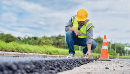 Construction worker reviewing new asphalt layer on roadwork site