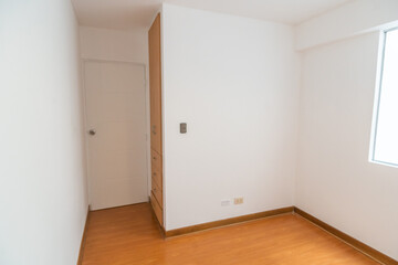habitacion de departamento con closet empotrado o incorporado, con acabdos en melamina en habitacion moderna con piso de madera y paredes blancas