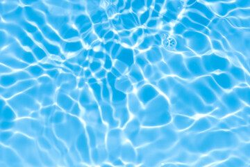 Blue water with ripples on the surface. Defocus blurred transparent blue colored clear calm water surface texture with splashes and bubbles. Water waves with shining pattern texture background.