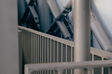 Abstract view of a modern architectural structure featuring metal beams and a rail during daylight