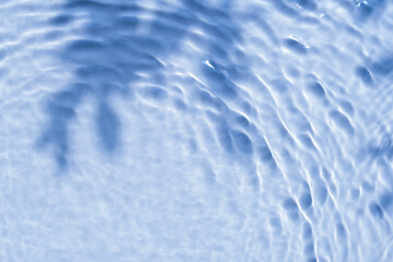 Background summer natural blue texture, clear water with ripples and splashes. Water waves in sunlight with leaf shadow, and background concept of cosmetics, moisturizer, and toner.	
