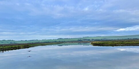 Tranquil lake reflection with hills and sky.