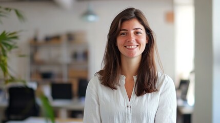 Obraz premium Portrait of a smiling woman wearing a white shirt, standing in an office.