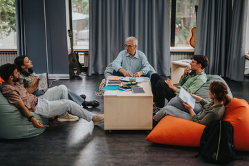 A professor engages with students in a relaxed classroom setting. The group seated on bean bags represents informal learning and collaborative discussion, fostering educational interaction.