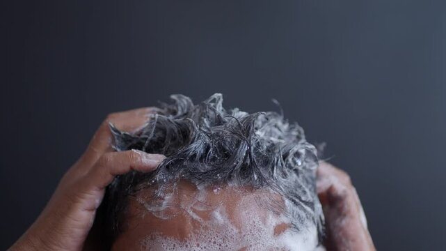 young men washes h his hair with shampoo .