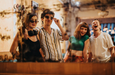 A joyful group of friends in stylish attire poses playfully for a photo in a cozy and vibrant cafe setting. They are enjoying each other's company and capturing memories.