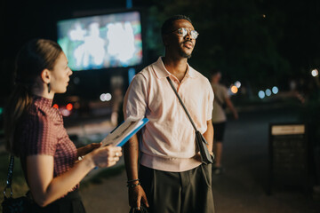 Two diverse business professionals engage in a collaborative brainstorming session during a late night meeting. The outdoor setting adds to the strategic and innovative atmosphere.