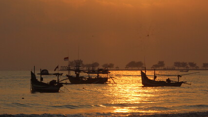 silhouette of a boat on the sea behind the red rising sun in the morning