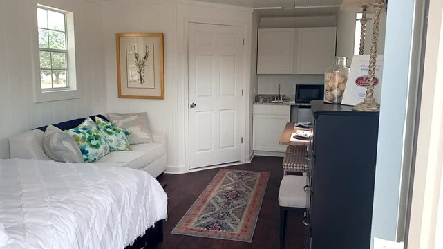 The interior of a tiny home features a bed, a bathroom, storage, compact kitchen, natural light, and eco-friendly design