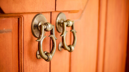 Obraz premium The front view and antique door handle made of old and shiny metal on an old wooden door, is the gate of a palace