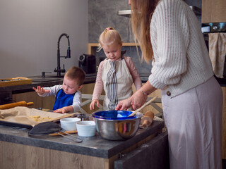 Mother mixing cookie dough in a bowl, children arranging cookies on a baking sheet, enjoying family time together in a modern kitchen setting, creating homemade treats and learning valuable skills