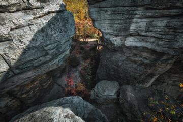 A breathtaking view of rocky cliffs framing a narrow passageway, revealing vibrant autumn foliage and textured stone surfaces, inviting exploration and adventure