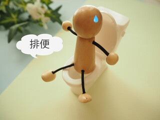 トイレに座っている人形、排便の文字