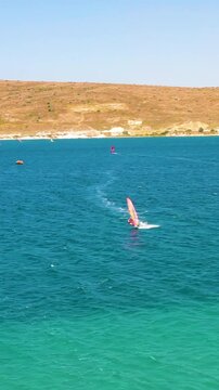 Vertical video of windsurfers - high quality aerial shot with drone of surfers windsurfing on Izmir beach in Aegean Sea Turkey Izmir