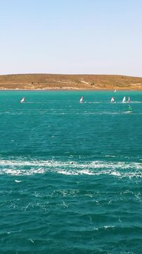 Vertical video of windsurfers - high quality aerial shot with drone of surfers windsurfing on Izmir beach in Aegean Sea Turkey Izmir