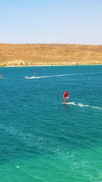 Vertical video of windsurfers - high quality aerial shot with drone of surfers windsurfing on Izmir beach in Aegean Sea Turkey Izmir