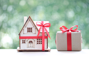 Model house and gift box with red ribbon for Christmas and New Year's Day or Greeting season,Real estate and Gift new home concept