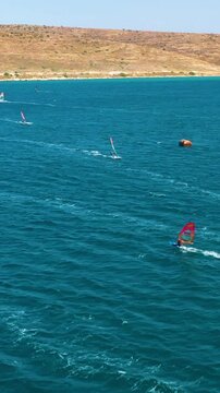 Vertical video of windsurfers - high quality aerial shot with drone of surfers windsurfing on Izmir beach in Aegean Sea Turkey Izmir