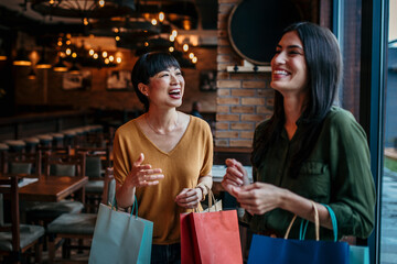 Women waking together after shopping and smiling