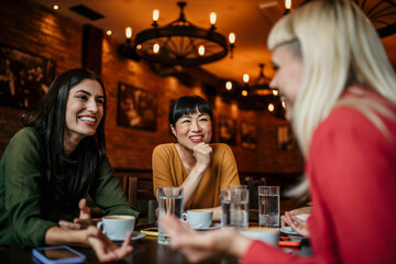 Happy small group of multiracial friends chatting and enjoying together in a café