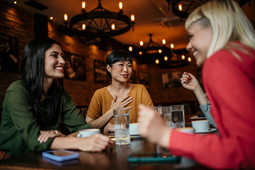 Happy small group of multiracial friends chatting and enjoying together in a café