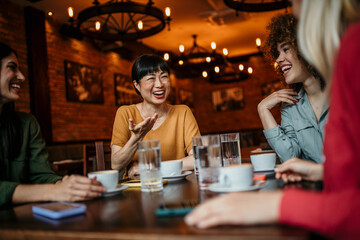Happy small group of multiracial friends chatting and enjoying together in a café