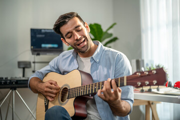Obraz premium Caucasian man play guitar and produce electronic soundtrack at home. 