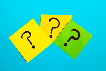 Three sticky notes with question marks on a blue background, question concept