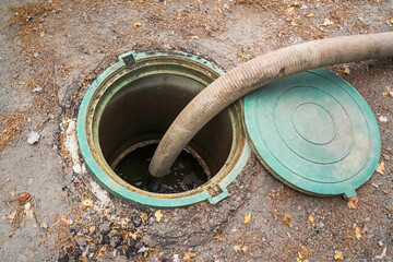 Pumping sewage. A vacuum hose extends into a green sewage tank, ready to extract waste. drainage...
