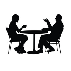 Two people sitting at a table. One of them is holding a cup. The table is round