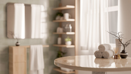 A round table features towels and decor objects with a blurred background of a clean bathroom.
