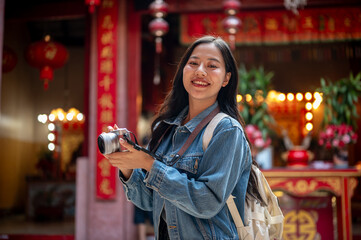 An attractive Asian female tourist visits a stunning Chinese shrine, enjoying her solo travels.