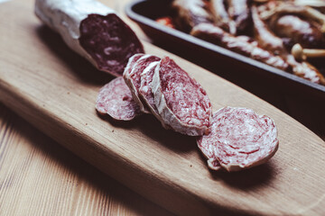 slices of traditional Spanish sausage salami fuet or dry sausage, covered with fermented mold on a wooden table.