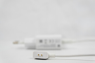 Fototapeta premium magnetic charging cable with two gold contact, a charging cable for smartwatch or a fitness tracker on white background