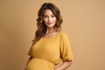 Fototapeta premium A pregnant woman is wearing a yellow dress and smiling