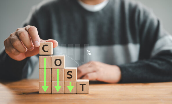 Lean or Cost reduction concept. Optimize manufacturing management. Decreasing company expense to maximize profits. Hand puts a wooden cube with words cost and green down arrows. Business improvement.
