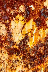 Close-up of rusted and decayed metal. The surface has a layer of oxidation with a slight orange, brown, and yellow and white tint. texture and background