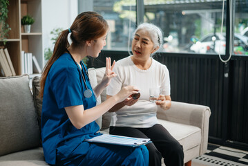 Fototapeta premium Asian caregiver doctor examine older patient woman therapist nurse at nursing home taking care of senior elderly woman sit on sofa.Medical service concept.