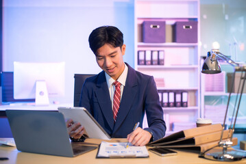 Businessman drinking coffee to get some energy for working overtime sitting at desk using computer and doing overtime