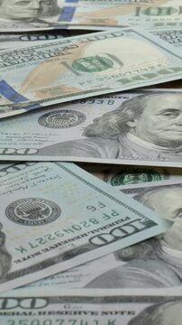 Various denominations of U.S. dollar bills are scattered on a surface, displaying detailed designs. The currency highlights the vibrant colors and symbols of American money.