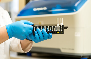 Tech managing test tubes in lab. A laboratory technician in gloves carefully manages test tubes in a research facility during a scientific experiment.