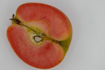 Cut in half kissabel apple against white background. Hidden rose apples, pink inside apple