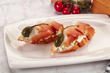 Bruschetta with jamon and caper berries
