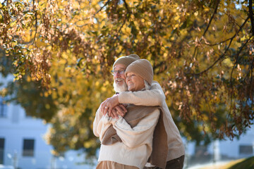 Portrait of beautiful senior couple during walk in autumn park. Elderly husband and wife are...