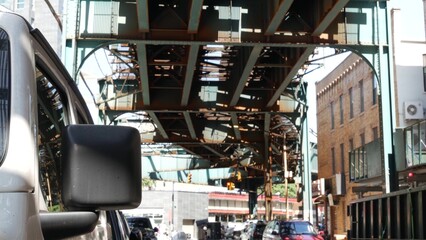 Elevated subway above New York city street. Metropolitan bridge over road, Queens. Long Island overhead metro line, Court Square, United States. Cars and diner under vintage railway track. Urban life.