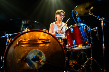 Female drummer performing live on stage with drum kit