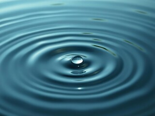 A delicate droplet of clear water floats on a bed of gentle circular ripples in a calm body of water, clear water, calming atmosphere
